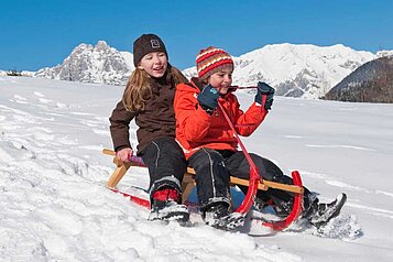 Kinder rodeln voller Freude die Piste hinunter in Südtirol im Familienhotel Alphotel Tyrol Wellness & Family Resort.
