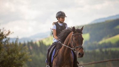Ein Mädchen reitet auf einem Pferd beim Familienhotel Der Ponyhof in der Steiermark