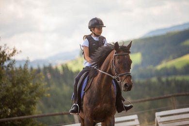 Ein Mädchen reitet auf einem Pferd beim Familienhotel Der Ponyhof in der Steiermark