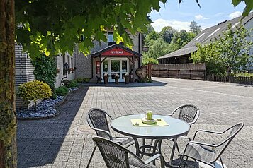 Einladender Außenbereich mit Tisch und Stühlen vorm Eingang des Familienhotels Monikas Ferienhof im Sauerland. 