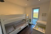 Kinderzimmer mit Etagenbett, Babybett und Zugang zur Terrasse im Familienhotel Gut Landegge