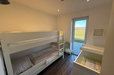 Kinderzimmer mit Etagenbett, Babybett und Zugang zur Terrasse im Familienhotel Gut Landegge