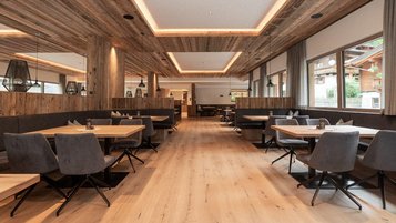 Modernes Restaurant mit Holzdesign und gemütlichen Sitzbereichen im Familienhotel Oberkarteis.