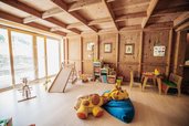 Heller Kinderspielraum mit Holzinterieur, Rutsche und Spielzeug im Wellness- & Familienhotel Egger.