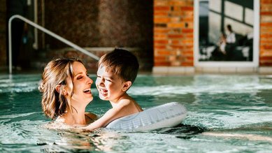 Eine Mama schwimmt mir Ihrem Sohn im Schwimmbad vom Familienhotel Landhaus Averbeck.