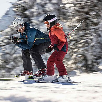 Vater und Tochter beim gemeinsamen Skifahren im Winter