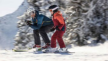 Vater und Tochter beim gemeinsamen Skifahren im Winter