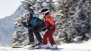 Vater und Tochter beim gemeinsamen Skifahren im Winter