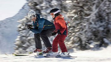Vater und Tochter beim gemeinsamen Skifahren im Winter