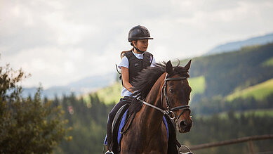 Ein Mädchen reitet auf einem Pferd beim Familienhotel Der Ponyhof in der Steiermark