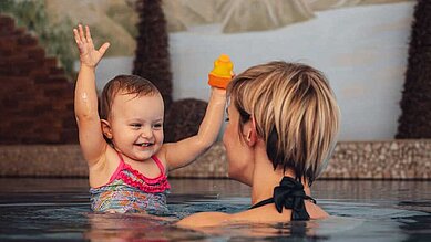 Mutter mit Baby im Indoor-Pool im Hallenbad des Familienhotels Alphotel Tyrol Wellness & Family Resort in Südtirol.