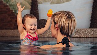 Mutter mit Baby im Indoor-Pool im Hallenbad des Familienhotels Alphotel Tyrol Wellness & Family Resort in Südtirol.