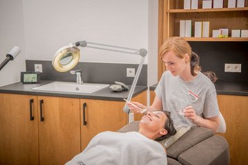 Entspannte Gesichtspflege im Landgut Furtherwirt Wellnessbereich, Kosmetikerin verwöhnt eine lächelnde Frau mit einer Beauty-Behandlung