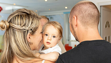 Eltern geben ihr Baby bei der Babybetreuung im Familienhotel Kaiserhof an der Zugspitze ab.