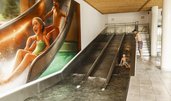 Drei Kinder rutschen die Triple Slide Rutsche des Almfamilyhotels Scherer hinunter.