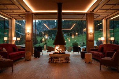 Gemütlicher Loungebereich mit Kamin und Panoramablick auf die Berge im Familienhotel Bella Vista in Südtirol.