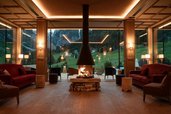 Gemütlicher Loungebereich mit Kamin und Panoramablick auf die Berge im Familienhotel Bella Vista in Südtirol.