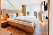 Helles Schlafzimmer mit Doppelbett aus Holz, Balkonzugang und Blick ins Grüne im Hotel Engel im Schwarzwald