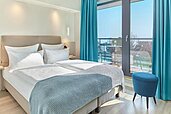 Doppelbett mit Zimmer mit Aussicht nach draußen mit viel Tageslicht im Familienhotel Strandkind an der Ostsee