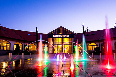 Das Familienhotel Kolping Hotel Spa & Family Resort in Ungarn bei Dunkelheit mit schöner, bunter Beleuchtung.