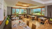 Heller Speisesaal mit großen Fenstern und Kindersitzmöglichkeiten im Familienhotel mit Blick auf die Berge