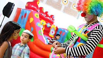 Ein Clown bläst Luftballons auf einem Kindergeburtstag auf