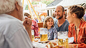 Familie sitzt im Biergarten und genießt Münchner Spezialitäten.