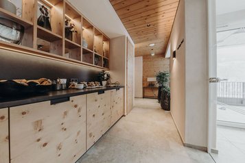 Gemütliche Snackbar mit Holzelementen und Teestation im Wellnessbereich des Familienhotel Habachklause.