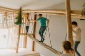 Im Spielbereich des Familienhotel Friedrichshof balancieren Kinder auf einer Hängebrücke aus Seilen.