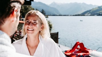 Eltern entspannen im Bademantel mit Seeblick im Familienhotel Amiamo im Salzburger Land.