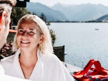Eltern entspannen im Bademantel mit Seeblick im Familienhotel Amiamo im Salzburger Land.