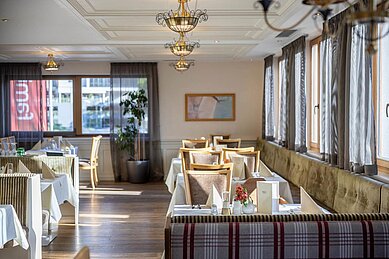 Restaurant mit einer großen Sitzbank und viel Tageslicht im Familienhotel Das Hopfgarten in Tirol.