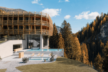 Außenansicht des Hotels Bella Vista in Südtirol mit Pool und herbstlich gefärbtem Wald.