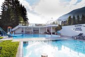Außenpoolanlage im Familienhotel Egger mit Relaxpool, Sportpool und Kinderrutsche, umgeben von Bergen und Natur.