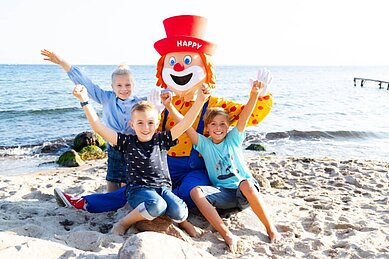 Kinder mit Maskottchen Happy am Strand am Familienhotel Strandkind an der Ostsee
