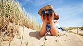 Kind mit Fernglas am Strand beim Familienhotel Strandkind an der Ostsee