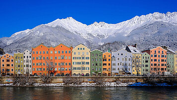 Bunte Häuser in Innsbruck. Im Hintergrund zu sehen sind die beschneiten Berge.
