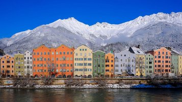 Bunte Häuser in Innsbruck. Im Hintergrund zu sehen sind die beschneiten Berge.