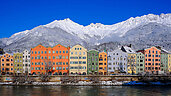 Bunte Häuser in Innsbruck. Im Hintergrund zu sehen sind die beschneiten Berge.