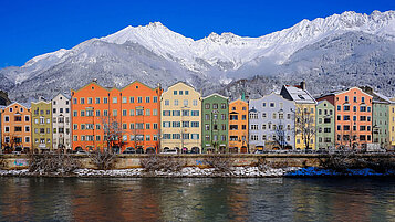 Bunte Häuser in Innsbruck. Im Hintergrund zu sehen sind die beschneiten Berge.