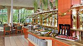 Blick auf das reichhaltige Abendbuffet mit frischen Salaten und Beilagen im Restaurant des Familienhotels Sonnenhügel, umgeben von großen Fenstern mit Ausblick auf grüne Bäume.