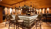 Große Bar mit gemütlichen Bar-Stühlen und angenehmer Beleuchtung im Familienhotel Das Bayrischzell in Oberbayern.