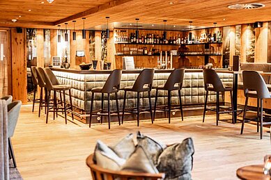 Große Bar mit gemütlichen Bar-Stühlen und angenehmer Beleuchtung im Familienhotel Das Bayrischzell in Oberbayern.