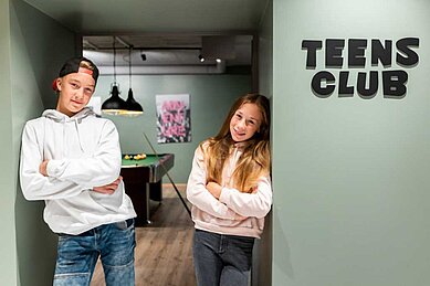 Zwei Teens stehen am Eingang des Teens-Clubs im Familienhotel Das Bayrischzell in Oberbayern.
