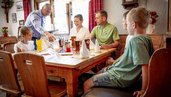 Familie wird vom Kellner beim gemeinsamen Essen im Restaurant des Familienhotels Krone im Allgäu bedient.