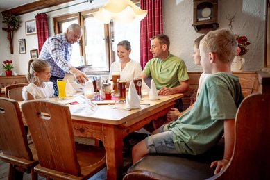 Familie wird vom Kellner beim gemeinsamen Essen im Restaurant des Familienhotels Krone im Allgäu bedient.
