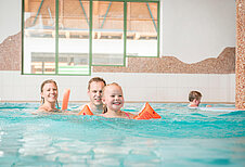 Eltern bringen ihrem Sohn im Schwimmbad des Familienhotels Landgut Furtherwirt das Schwimmen bei.