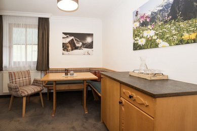 Heller Sitzbereich im Familienzimmer des Familienhotels Oberkarteis mit gemütlicher Eckbank, Holztisch und moderner Einrichtung.