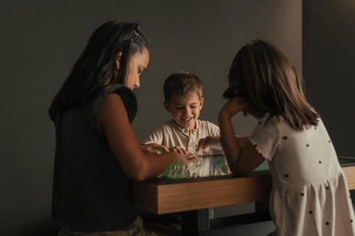 Kinder sitzen gespannt an einem Spieltisch und haben gemeinsam Spaß in ihrem Urlaub im Familienhotel Engel Gourmet & Spa in Südtirol