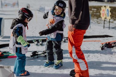 Kinder stehen beim Skikurs des Familienhotel Mia Alpina in Tirol mit Skiern im Schnee und werden betreut.